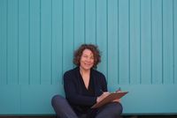 Kerstin sitzt vor einer blauen Mauer