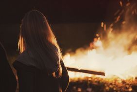 Junge Frau von hinten vor Lagerfeuer