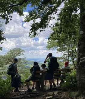 Jugendliche Wandergruppe ruht aus vor Bergpanorama