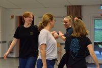 Vier Personen stehen in einem Raum und halten sich an den Händen, sie scheinen einen Tanz zu üben.