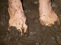 Füße ohne Socken im Schlamm.